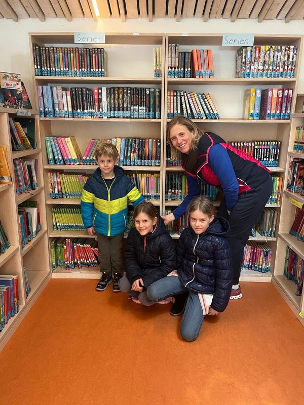 Mutter mit drei Kindern in der Bibliothek